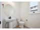 Small powder room with pedestal sink, toilet, and a window at 692 Apex Rise St, Erie, CO 80516