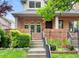 Close-up of the brick home's front entrance with steps, iron gate, and lush landscaping at 538 Cook St, Denver, CO 80206