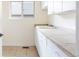 Bright laundry room features a tiled floor and counters, utility sink, window, and white cabinets for storage at 538 Cook St, Denver, CO 80206