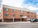 A multi-story red brick building with an awning-covered entrance and parking space at 155 S Pennsylvania St # 310, Denver, CO 80209