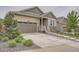Attractive home showcasing a driveway, two-car garage, stone accents, and meticulous landscaping with green bushes at 8153 S Ider Ct, Aurora, CO 80016