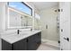 Modern bathroom featuring double vanity, large lighted mirrors, and a glass-enclosed shower with tile surround at 1252 Yates St, Denver, CO 80204