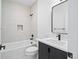 Modern bathroom featuring a tub with light stone-look tiling, matte black fixtures, and a vanity at 1252 Yates St, Denver, CO 80204