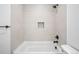 Stylish tiled bathtub and shower combination featuring a built-in niche, black fixtures, and white tiling at 1252 Yates St, Denver, CO 80204