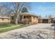 Charming brick home with a large front yard and a detached garage accessible via a long driveway at 2562 S Xavier St, Denver, CO 80219