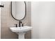 This powder room features vertical tile, a black faucet and mirror, and a white sink at 7392 Timberstone St, Castle Pines, CO 80108