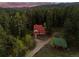 Stunning aerial perspective highlighting a home and detached garage set within a dense forest landscape at 8821 Blue Creek Rd, Evergreen, CO 80439