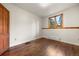 Bright bedroom features wood floors, trim, and a large window offering plenty of natural light at 8821 Blue Creek Rd, Evergreen, CO 80439