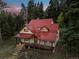 Charming home featuring a red metal roof, covered porch, and a stone stairway at 8821 Blue Creek Rd, Evergreen, CO 80439