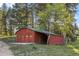 Exterior photo of a red wood-sided garage with a green roof nestled in a forest setting at 8821 Blue Creek Rd, Evergreen, CO 80439