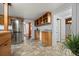 Galley-style kitchen with wood cabinets, stainless steel refrigerator, and view into entry area at 8821 Blue Creek Rd, Evergreen, CO 80439