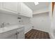 Functional laundry room features ample storage with white cabinets, a utility sink, and tiled flooring at 8821 Blue Creek Rd, Evergreen, CO 80439
