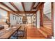 Open-concept living room with stone fireplace, wood beams, and hardwood floors at 8821 Blue Creek Rd, Evergreen, CO 80439