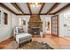 Living room featuring exposed beams, a stone fireplace, and hardwood floors at 8821 Blue Creek Rd, Evergreen, CO 80439