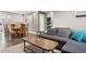 Open-concept living room featuring modern gray sofa, coffee table and wood dining set adjacent to bright kitchen area at 8481 Dawson Dr, Denver, CO 80229