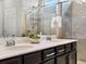 Bright bathroom featuring double sinks, dark wood cabinets, quartz countertops, and a glass-enclosed shower at 5205 Periwinkle Way, Brighton, CO 80640