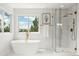 Modern bathroom featuring a soaking tub, a glass enclosed shower with marble surround, and bright windows at 9117 Buck Hill Dr, Highlands Ranch, CO 80126