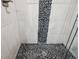 Close up of modern shower with pebble floor, stone-look tiling and glass door at 8095 E 128Th Pl, Thornton, CO 80602