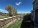 A fenced backyard features a small greenhouse and a view of an open field at 2005 W 86Th Ave, Denver, CO 80260