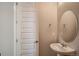 Elegant powder room featuring a pedestal sink, oval mirror, and a door, for a functional space at 2560 Wesley Ln, Lafayette, CO 80026