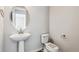 Modern powder room featuring a pedestal sink, stylish mirror, and toilet at 2560 Wesley Ln, Lafayette, CO 80026