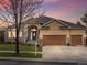 Charming single-Gathering home at twilight featuring a three-car garage, stone accents, and a manicured front yard at 5497 W Prentice Ct, Littleton, CO 80123