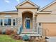Inviting front porch with stone accents, a blue door, and well-maintained landscaping at 5497 W Prentice Ct, Littleton, CO 80123