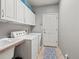 Bright laundry room with washer, dryer, sink, and storage cabinets at 5497 W Prentice Ct, Littleton, CO 80123
