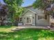 Backyard showcasing a stone patio area surrounded by lush lawn and mature trees providing shade at 6525 S Abilene St, Englewood, CO 80111