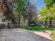 Outdoor patio with a small lawn, mature trees and shrubs, and a wood fence surrounding the yard at 6525 S Abilene St, Englewood, CO 80111