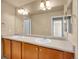 Well-lit bathroom featuring double vanity sinks, neutral countertop, and large mirror at 6525 S Abilene St, Englewood, CO 80111