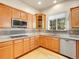 Well-lit kitchen with stainless steel appliances, wood cabinetry, and a view of the backyard at 6525 S Abilene St, Englewood, CO 80111