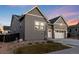 View of a modern gray home with stone detailing, a two-car garage, and landscaped front yard at 11412 Autumn Moon St, Littleton, CO 80125