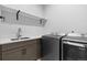 Modern laundry room with gray front load washer and dryer, white countertop, and floating shelf at 11412 Autumn Moon St, Littleton, CO 80125