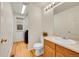 A well-lit bathroom with wood floors, a vessel sink, and a closet with a modern washing machine at 15112 E 116Th Pl, Commerce City, CO 80603