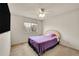 Bright bedroom features a ceiling fan, large window, and comfortable bed with purple linens and a decorative pillow at 15112 E 116Th Pl, Commerce City, CO 80603