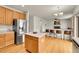 Open-concept kitchen with an island, stainless steel refrigerator, and bar seating at 15112 E 116Th Pl, Commerce City, CO 80603