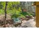 Cozy backyard seating area features stone patio, mature trees and shed in a lush natural setting at 7364 Rossman Gulch Rd, Morrison, CO 80465