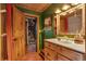 Bright bathroom featuring a shower over tub, natural wood vanity, and a green accent wall at 7364 Rossman Gulch Rd, Morrison, CO 80465