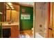 Bright bathroom featuring a shower over tub, natural wood vanity, and a green accent wall at 7364 Rossman Gulch Rd, Morrison, CO 80465