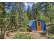 Exterior shot of a well-maintained storage shed, surrounded by trees and lush vegetation at 7364 Rossman Gulch Rd, Morrison, CO 80465