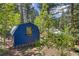 Exterior view of a blue storage shed in a lush wooded environment with mature trees at 7364 Rossman Gulch Rd, Morrison, CO 80465