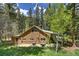 Exterior view of a rustic home, lush greenery, mature trees and a built in grill at 7364 Rossman Gulch Rd, Morrison, CO 80465