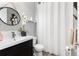 Bathroom featuring a dark vanity with white sink, white shower curtain and round mirror at 11582 Jimenez St, Parker, CO 80134