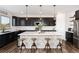 Stylish kitchen with dark cabinets, a large white island with seating, and modern pendant lighting at 11582 Jimenez St, Parker, CO 80134