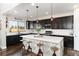 Modern kitchen featuring dark cabinets, a large island with seating, and stainless-steel appliances at 11582 Jimenez St, Parker, CO 80134