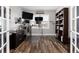Home office with hardwood floors, dual monitors, and built-in shelving for organized work at 11582 Jimenez St, Parker, CO 80134