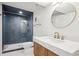 Modern bathroom with a walk-in shower, round mirror, wood cabinets, and marble countertops at 6279 E Princeton Ave, Cherry Hills Village, CO 80111