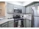 Updated kitchen features stainless steel appliances, grey cabinets, granite countertops, and white tile backsplash at 6001 S Yosemite St # B206, Greenwood Village, CO 80111