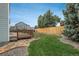 The backyard offers a stone path leading to the deck, complemented by lush green grass and mature trees at 23955 Glenmoor Way, Parker, CO 80138